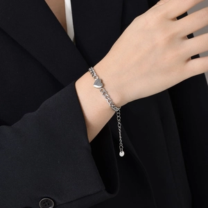 Detailed view of silver stainless steel heart pendant bracelet on model's wrist