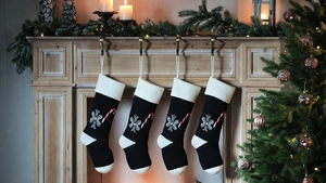 Detail of four black knit Christmas stockings with white snowflakes and candy cane patterns