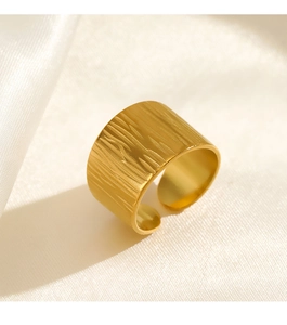 Macro view of wide gold plated stainless steel ring with bark texture on satin background