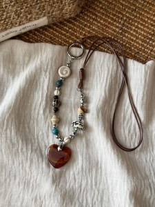 Detail of bohemian necklace with multi-material beads and amber heart pendant