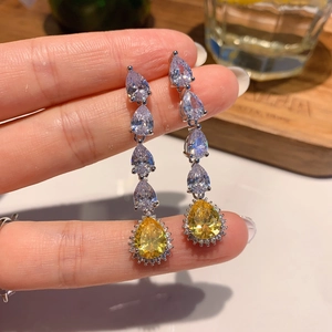Close-up of teardrop pear-cut yellow diamond earrings with sparkling white zircon stones