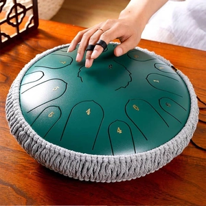 Detail of playing dark green steel tongue drum with black finger picks on wood surface