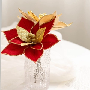 Detail of red and gold artificial poinsettia in glass vase for Christmas decor