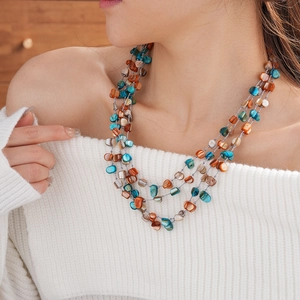 Close-up of multilayered bead necklace with irregular blue and brown shell stones on a model