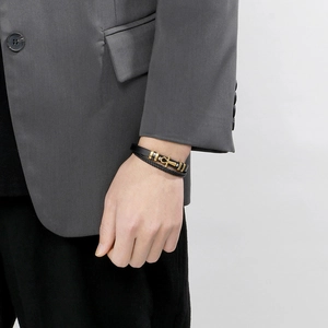 Detail of woven leather bracelet with golden anchor clasp worn on a man's wrist