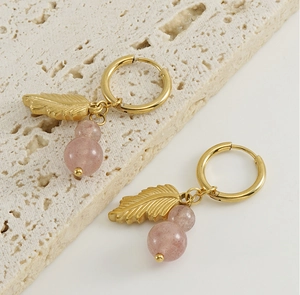 Detail of 18K gold stainless steel hoop earrings with feather charm and pink sea urchin stone