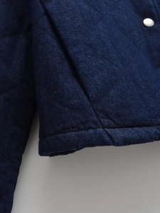 Macro shot of dark blue denim quilted fabric with shiny silver metal buttons