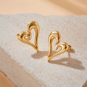 Elegant gold hollow heart earrings with asymmetric minimalist design on stone background