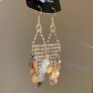 Detail view of long tassel earrings with sparkling rhinestones and golden leaf charms