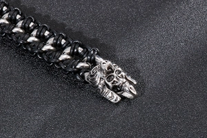 Detailed close-up of punk style braided black leather bracelet with steel skull clasp