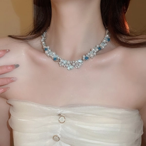 Detail of layered pearl necklace with blue opal stones worn on a female model
