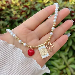 Detail of 18K gold plated beaded necklace with red heart, saint medal, and gold cross