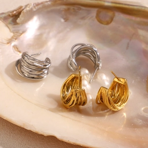 Close-up of gold and silver multi-layer C-shaped hoop earrings inside an iridescent shell