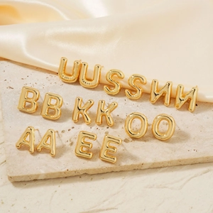 Golden 3D balloon alphabet stud earrings with a polished finish on stone and silk
