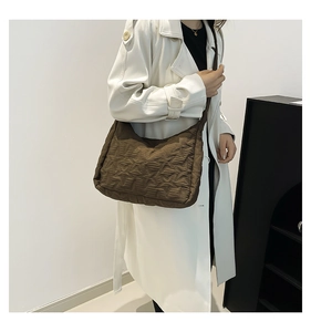 Detailed view of dark brown quilted tote bag with star patterns on a model wearing a coat
