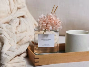 Dettaglio di fiori rosa stabilizzati e bastoncini in un diffusore di aromi in vetro