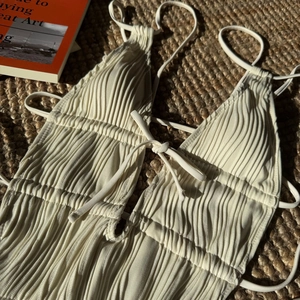Dettaglio macro del costume intero a pieghe crema con spalline sottili e coulisse