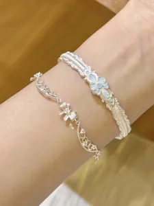 Détails d'un bracelet en argent avec nœud et manchette vintage à fleurs en émail