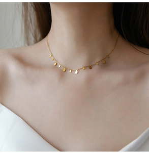 Close-up of elegant gold titanium steel necklace with small teardrop pendants on skin