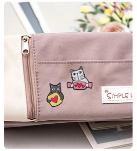 Detail of cute cat alloy badges and heart pins on a pink fabric stationery pencil bag