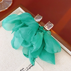 Details von grünen Chiffon-Blumenohrringen mit Kristallen auf einem Holzdisplay