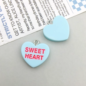 Macro shot of light blue heart-shaped resin charms with SWEET HEART text on vintage paper