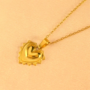 Detail of gold heart pendant featuring radial sunburst texture and polished center