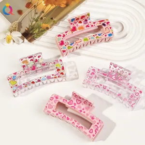 Detailed view of four large acrylic hair claws with colorful heart patterns for women