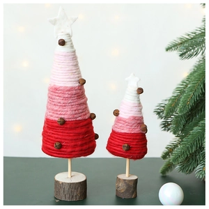 Handcrafted wool felt Christmas trees with metal bells and wood base in warm holiday light