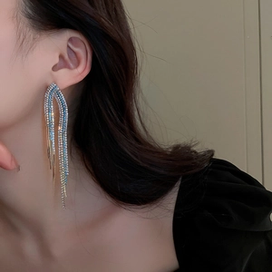 Close-up of long tassel earrings with blue and clear rhinestones worn by a model