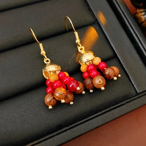 Close-up of Bohemian wood and orange glass beads drop earrings on black jewelry display