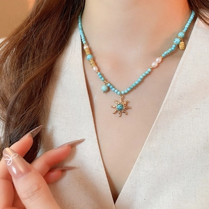 Détail du collier pendentif soleil avec perles turquoise et perles d'eau douce