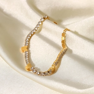 Dettaglio del bracciale a farfalla dorata con zirconi bianchi su elegante seta bianca