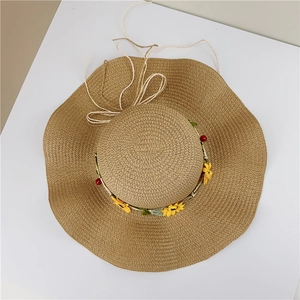 Detail of wide brim straw sun hat with yellow sunflowers and red berry decoration