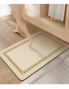 Detail view of beige diatomaceous earth bath mat with decorative brown border on wood floor