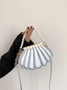 Detail of silver shell-shaped handbag with pearl chain handle and metallic luster