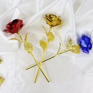Close-up of red, gold, and blue metallic roses lying on elegant white silk fabric