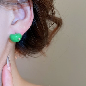 Close-up of green apple stud earring with enamel finish and rhinestone on the ear