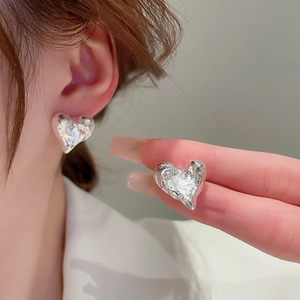 Boucles d'oreilles cœur en argent au fini texturé lave portées par un modèle