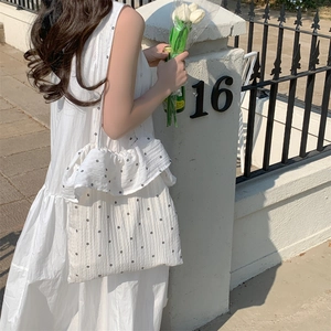 Detail of white canvas tote bag with floral patterns and ruffled chiffon edge in outdoor setting