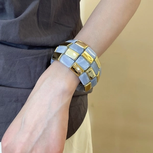 Detail of blue marbled resin and golden metal blocks on a three-row elastic bracelet