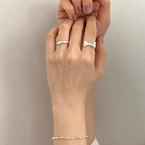 Detail of 925 sterling silver bow ring and bracelet set worn on a model hand