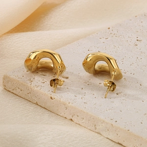 Macro detail of 18K gold-plated titanium earrings with irregular geometric wave design