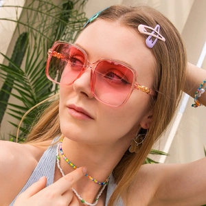 Detail of square oversized sunglasses with pink gradient lenses and gold metal temples
