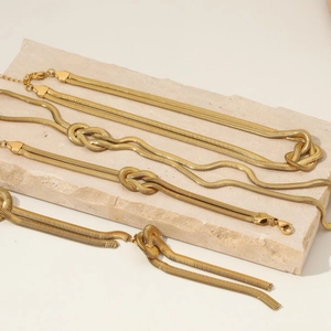 Set collana e bracciale a catena serpente dorata con nodo su lastra di pietra