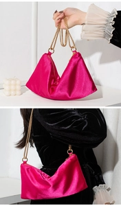 Detail of fuchsia satin tote bag with gold chain strap on black velvet clothing