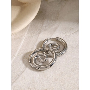 Vue macro de boucles d'oreilles spirales argentées avec un design géométrique poli en acier