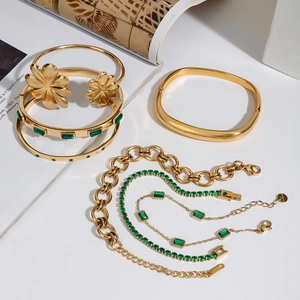 Set di bracciali in acciaio inossidabile dorato con zirconi verdi su fondo bianco