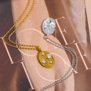 Hammered gold and silver oval zircon pendant necklaces on a vintage magazine background