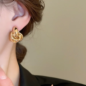 Nahaufnahme der goldenen verschlungenen Knoten-Ohrstecker an einem Model getragen